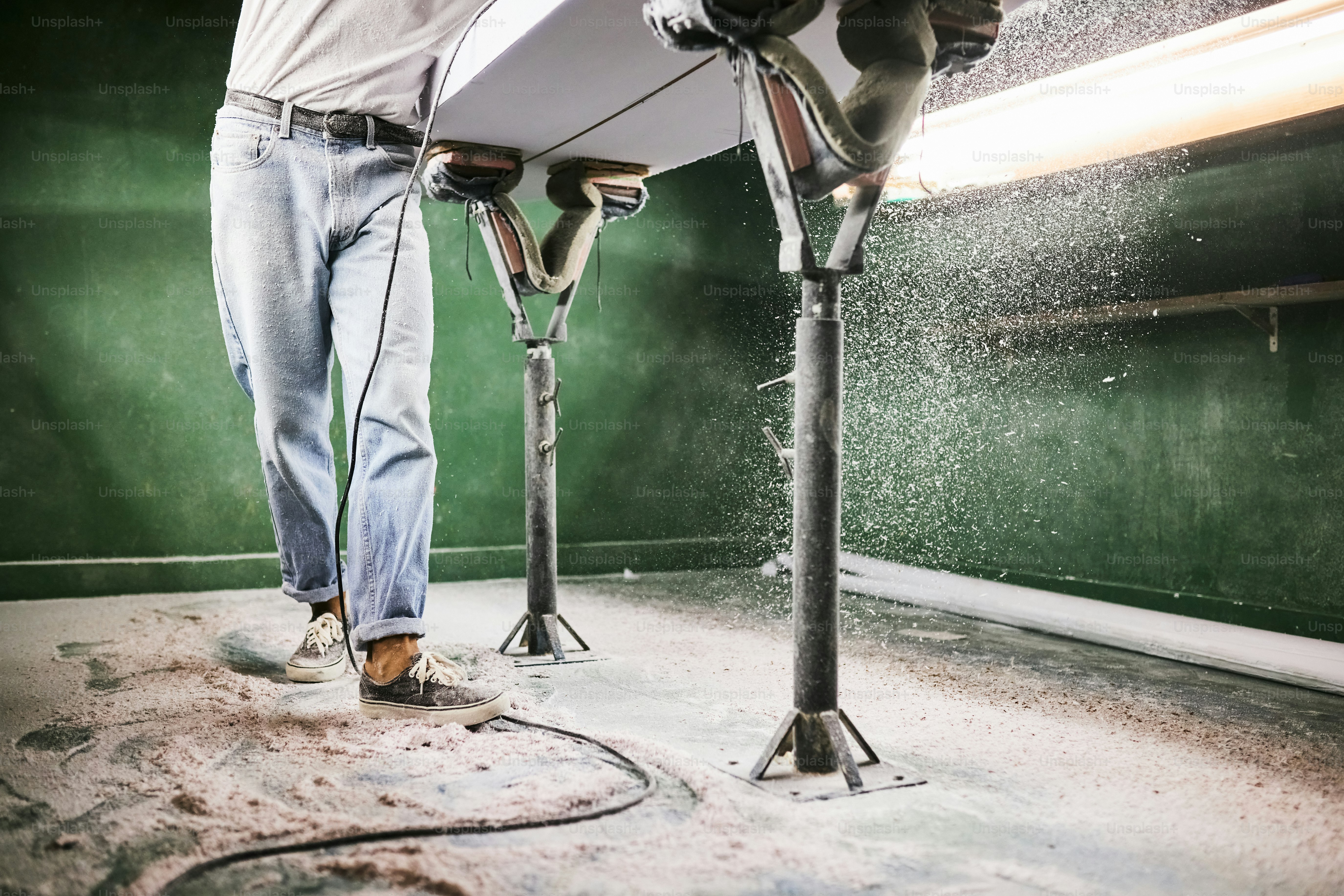 A man polishes a board in a workshop.
